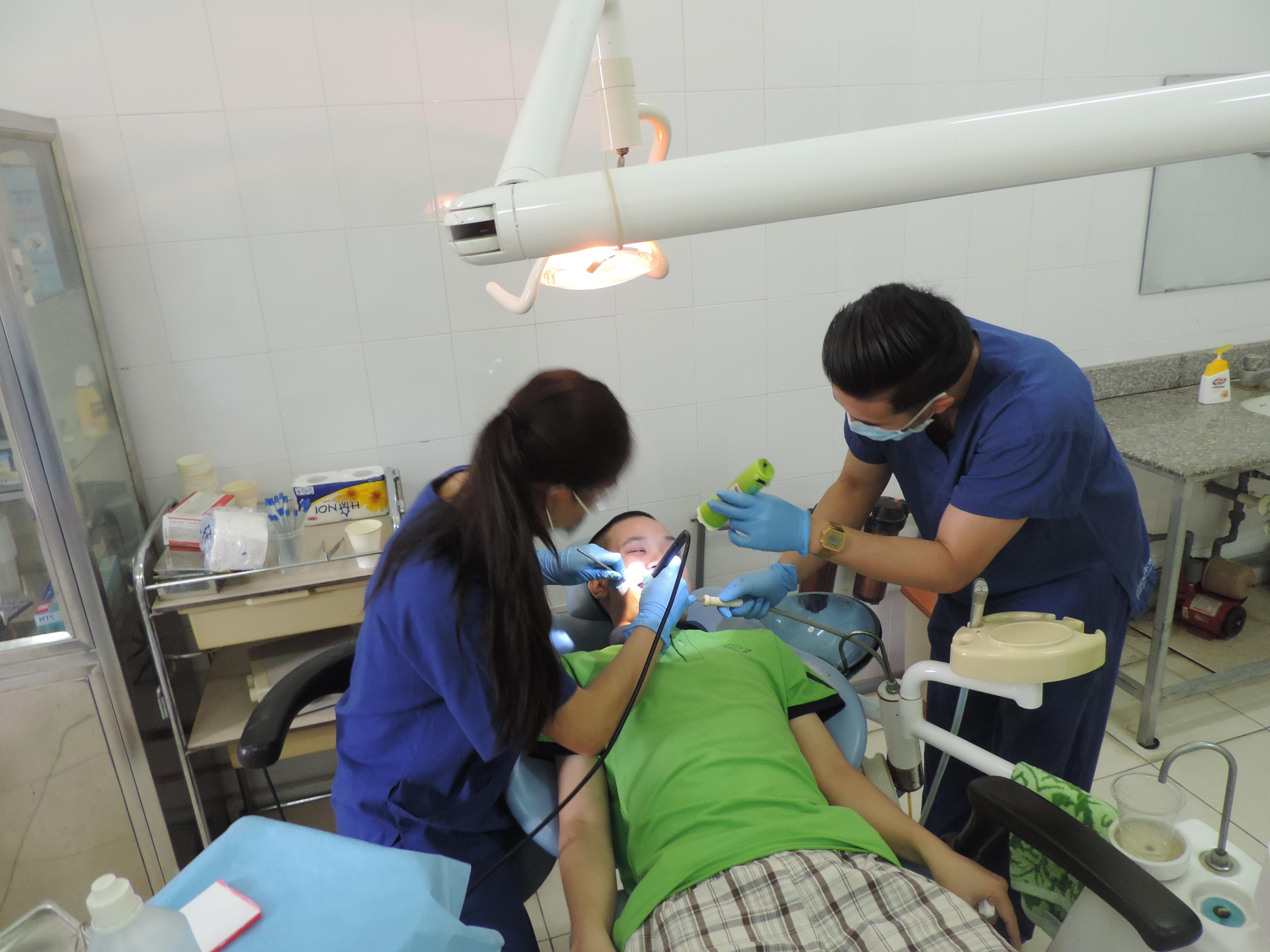 A student assists a local dentist during a procedure on the Projects Abroad Dentistry Internship in Vietnam. An intern gains dental work experience in Vietnam by helping a local dentist as he works with a patient.